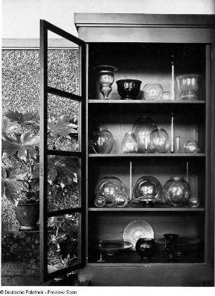 Interieur (geöffneter Vitrinenschrank mit Glassammlung und Blumentöpfen)