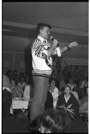 Stormarnia Ahrensburg 1989: Komiker Fips Asmussen steht auf einer Bühne und spricht vor Publikum ins Mikrofon