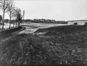 Gehöfte : Blick über einen Acker auf Gehöfte. Links eine Straße mit Bäumen