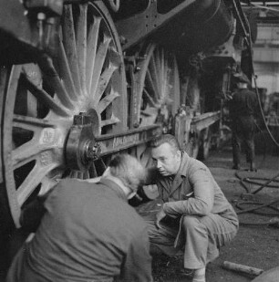 Zwei Werkstatt-Eisenbahner am Laufwerk einer Dampflokomotive (Serie Deutsche Reichsbahn - Brigade "Otto Buchwitz")