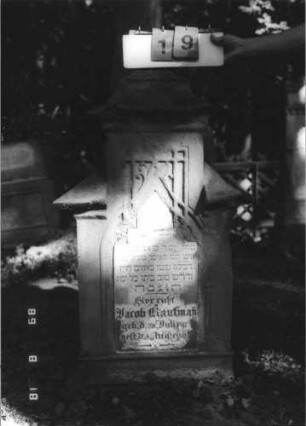 Grabstein 19 (Index: 100109162) Material: Sandstein und Marmor Zustand: stark verwittert, Schrifttafel zerbrochen und repariert Maße HxBxT: 129x72x31 cm Beschreibung: Stele auf Sockel, Abschluß Sonderform, Schrifttafel eingesetzt mit Maßwerk, Abschluß Sonderform Besonderheit: unehelich: Grabstein 19