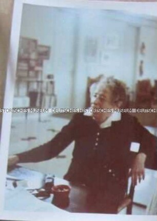Hannah Arendt an einem Tisch sitzend