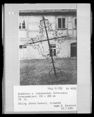 Grabkreuz eines Unbekannten (Schmiedes). Schmiedeeisen; 153 x 208 cm. 18. Jahrhundert. Blick gegen ein Gebäude (Teilansicht). Oßling, Friedhof