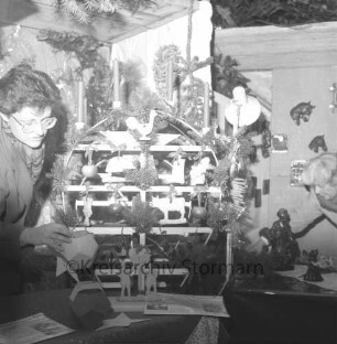 Rethwischdorf: Grundstück des stellvertretenden Kreispräsidenten Ernst Eick: Weihnachtsmarkt: Marktstand mit Weihnachtsleuchter und Tannendekoration: links Frau
