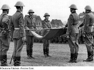 Waren (Müritz). Nationale Volksarmee - Landstreitkräfte. Öffentliche Vereidigung neu in das Panzerregiment 8 (PR-8) einberufener Wehrpflichtiger. Fahnenkommando (links) und Schwursoldaten mit Hand an der entfalteten Truppenfahne