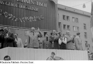 Blick auf die Tribüne mit Otto Grotewohl (2.v.l.), Erich Uhlich (3.v.l.) und Max Reimann (2.v.r.) auf der Straße der III. Weltfestspiele (heutige Jahnallee)