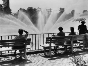 Hamburg-St. Pauli. Wasserspiel am Parksee in der Parkanlage "Planten un Blomen" Pflanzen und Blumen. Besucher sitzen auf Bänken
