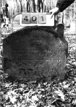 Grabstein 401 (Index: 99752654) Material: Sandstein Zustand: leicht verwittert/Stele eingesunken Maße HxBxT: 63x70x16 cm Beschreibung: Stele, Segmentbogenabschluß: Grabstein 401