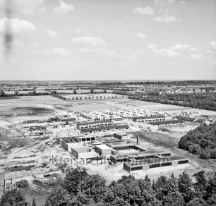 Volksschule Klosterbergen: Klosterbergenstraße: Blick vom Sachsenwald-Hochhaus Richtung Norden auf Klosterbergen: rechts Klassen- und Verwaltungstrakte: links Turnhalle und Lernschwimmbecken im Bau: dahinter Reihenhäuser und Atriumhäuser: im Hintergrund Felder, Baumreihen und Waldgebiete