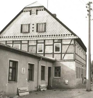 Königswalde (Kreis Annaberg). Wohnhaus mit Ladenanbau, August-Bebel-Straße 1. Straßenansicht mit Anbau (Konsum Industriewaren)