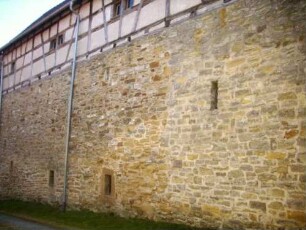 Nordflanke mit Kirchhofmauer und Gaden von Nordwesten (Kirchhofmauer als Außenmauer der Gaden mit Wehrgang und Schießscharten im oberen Bereich unterhalb der Fachwerk-Gadengeschosse)