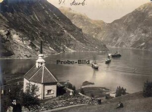 Merok/Norwegen. Blick auf die Bucht von Merok mit Kirche, im Hintergrund mehrere Passagierdampfer