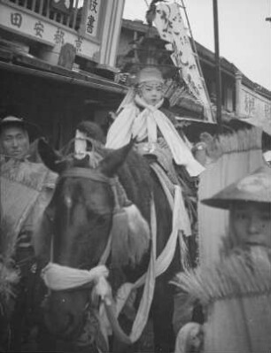 Kind in traditioneller Festkleidung, auf einem Pferd reitend : Tempelfest (O-matsuri), vielleicht das Yamabiki Matsuri im August. Kind in traditioneller Festkleidung, auf einem Pferd reitend