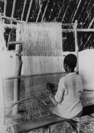 Man. Jeune tisserand fabriquant un tapis de raphia