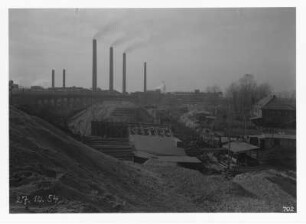 Industrie-Kraftwerk. Baustelle einer Eisenbahnbrücke (Grubenbahn über Werkgleis), im Hintergrund aufgeständerte alte Trasse der Grubenbahn und Werkanlagen mit Schornsteinen : Lauta (Niederlausitz). Industrie-Kraftwerk. Baustelle einer Eisenbahnbrücke (Grubenbahn über Werkgleis), im Hintergrund aufgeständerte alte Trasse der Grubenbahn und Werkanlagen mit Schornsteinen
