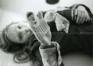 Mädchen liegt auf dem Boden und hält eine Handpuppe hoch (Altersgruppe 18-21)