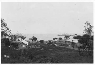 La Brea, Trinidad und Tobago. Passagierdampfer Moltke vor der Küste. Einheimische und Touristen vor den Häusern; rechts im Bild Industrieseilbahn für Asphalttransport vom Pitch Lake, die bis zur Landungsbrücke führt