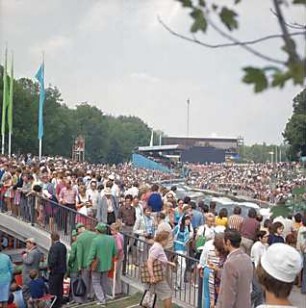 Hansjakob, Gottfried; Augsburg - Spickel, Am Eiskanal 30A; Kanuslalom Olympiastrecke, Freiflächengestaltung - Wettkampfstrecke während Olympiade, Tribünen und Brücke mit Zuschauern, Blick Richtung Norden