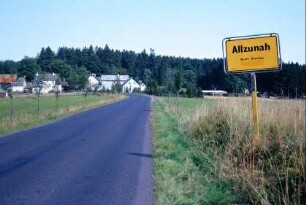 Ortseingang mit Ortseingangsschild; Straße mit neu gepflanzten Bäumen