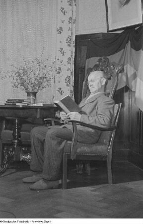 Älterer Mann lesend in einem Sessel sitzend