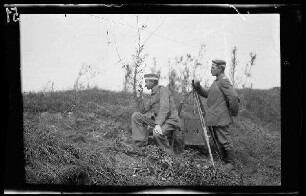 Nicht identifizierbare Ortschaft (Belgien?): 2 Soldaten mit einem Messgerät (Signalgerät?) an einer leichten Böschung (Seitansicht)