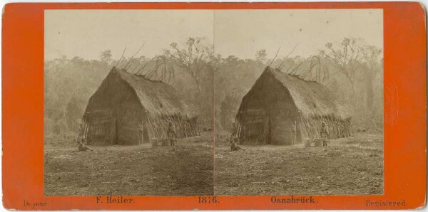 Three people in front of a hut