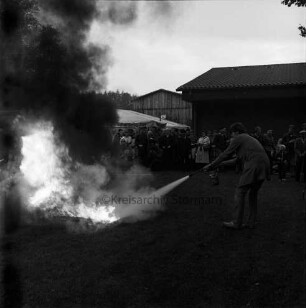 Freiwillige Feuerwehren Westerau, Trenthorst und Ahrensfelde: Feuerwehrübung "Waldbrand": Dorfteich: Löschen eines Benzinbrandes mit Handfeuerlöscher: rechts Feuerwehrmann: links Feuer: im Hintergrund Zuschauer und Häuser