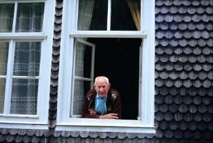 Herr Koch im Fenster, interessiert sich für die Ortsgeschichte, Besitzer der früheren Schmiede