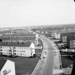 Gartenstadt Falkenberg: Blick vom Rathaus Richtung Osten: Stonsdorfer Weg mit parkenden Pkws auf Seitenstreifen: rechts und links Wohnblocks: dazwischen Grünflächen: im Hintergrund das Gewerbegebiet Stonsdorf