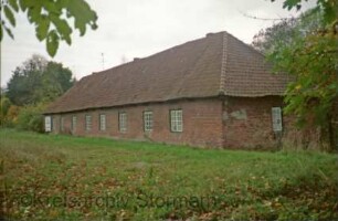 Blumendorf: "Lange Kate": Mehrfamilienkate aus Backstein mit Ziegeldach: traufständige Straßenfront mit Sprossenfenstern: hinten an Hausecke Reklameschild: Giebelseite