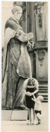 Junge Mutter mit Kind vor Statue