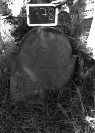 Grabstein 378 (Index: 100102865) Material: Sandstein Zustand: stark verwittert, abgeblättert, fast vollständiger Textverlust Maße HxBxT: 84x60x9 cm Beschreibung: Stele, eingezogener Rundbogenabschluss, Schriftfeld eingetieft Besonderheit: kulturhistorisch wertvoll / hist.-wiss. Gründe (Vorbeter): Grabstein 378