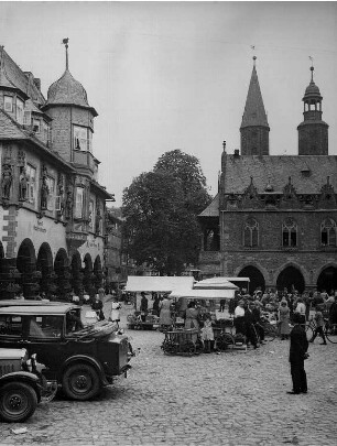 Goslar (Niedersachsen). Marktplatz mit Markttreiben. Links im Bild die Kaiserworth, das 1484 erbaute Gildhaus. Im Hintergrund das gotische Rathaus. Dahinter die Türme der erstmals 1151 erwähnten Marktkirche St. Cosmas und Damian.