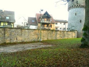 Stadtbefestigung-Ansicht im Süden mit Stadtmauer (Wehrgang mit Steinbrüstung abgetragen) über Feldseite (Graben verfüllt) mit Wehrturm (Simmelturm) im Südosten