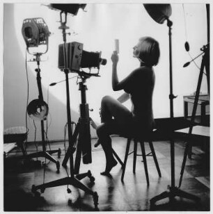 Junge Frau in einem Fotoatelier auf einem Hocker sitzend