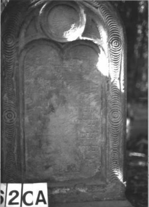 Grabstein 620 (Index: 99900659) Material: Sandstein Zustand: fast völlig verwittert Maße HxBxT: 160x50x18 cm Beschreibung: aufgesockelte Stele mit Rundbogenabschluss, Rahmen mit Scheibenfries, Innenrahmen mit Dreipassmaßwerk Symbolik: Scheibenfries: Grabstein 620A