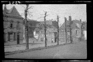 Mons (Belgien): Gebäudeensemble, im Vordergrund eine breite Straße mit einer kahlen Baumreihe (Distanzaufnahme)