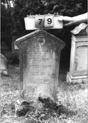 Grabstein 79 (Index: 100110804) Material: Sandstein Zustand: oberhalb des Sockels leicht verwittert Maße HxBxT: 98x49x14 cm Beschreibung: Stele, Sockel, giebelartiger Abschluß, Schriftfeld eingeteift Symbolik: 1 Rosette Besonderheit: Kindergrab: Grabstein 79