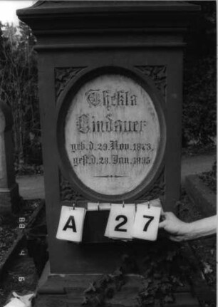 Grabstein 27 (Index: 99792859) Material: Sandstein und Marmor Zustand: Sockel und Giebel stark verwittert Maße HxBxT: 163x54x30 cm Beschreibung: Stele, Sockel profiliert, Giebel mit Akroter, Schriftfeld eingetieft, stehendes Oval, eingesetzte Textplatte Symbolik: Efeubätter: Grabstein 27A