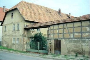 Hofmauer eines Bauernhofes mit neuerem Metallzaun als To