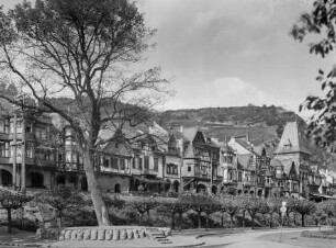 Rheinanlagen mit Lindenbaum in Bacharach, Blick auf die Rheinfront mit Gasthaus zu Linde, Haus Cramer und Marktturm, im Hintergrund die sogenannte Hitlerhöhe mit Hakenkreuz