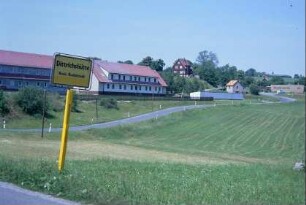 Ortsschild und Teilansicht des Ortes