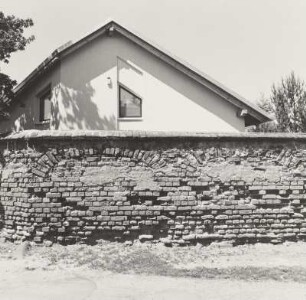 Teil der Gutsmauer mit dahinter liegendem Neubau