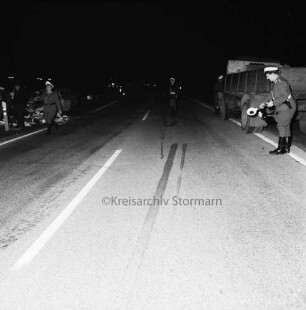 B 404: bei Tralau: Verkehrsunfall: Zusammenstoß von Pkw-Kombi mit Lkw: Straße mit Bremsspuren: drei Polizisten mit Kelle beim Sichern der Unfallstelle: links neben Straße Pkw-Kombi mit eingedrückter Front: rechts neben Straße Lkw: im Dunkeln, 12. Januar 1965