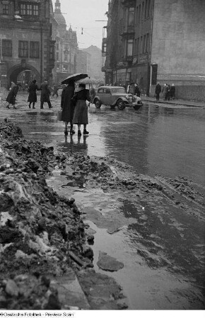 Passanten am Markt im Regen, im Hintergrund das Alte Rathaus