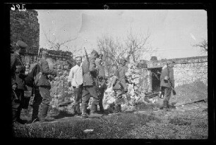 Nicht identifizierbare Ortschaft bei Saint-Laurent, Blangy oder Athies (alle Dep. Pas-de-Calais, Frankreich): Gruppe Soldaten mit Marschgepäck und Henkelmann auf einem Weg neben einer Gebäuderuine (Seitansicht)