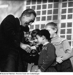 Fotograf Erich Pohl (1904-1968) mit Kindern, denen er seine Kamera vorführt. Dresden?