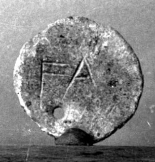 Runde durchbohrte Stimmmarke der Eleer mit griechischen Inschriften, auf der einen Seite ΔΙ, auf der anderen FA(leion)