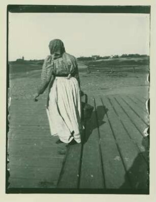 Frau mit Korb vor der Silhouette der Westend-Kolonie, Rückansicht 1 v. 2.