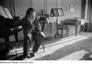 Portrait Roger Rössings neben einem Klavier sitzend